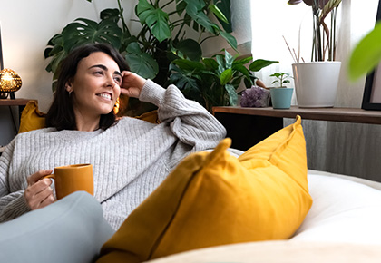 Woman seating on a couch drinking a beverage. High-Rise trends in Southern California