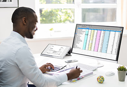 Man in front of a computer reading a report