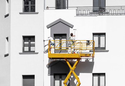 Two painters on a lift painting a building; tips for hiring a contractor