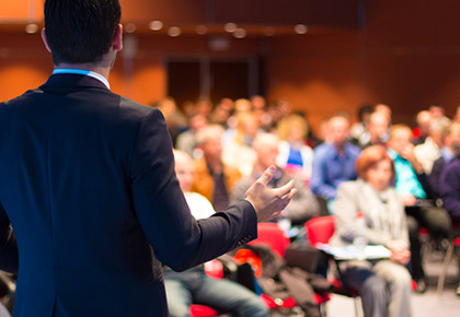 Main in suit talking in front of an audience - FirstService Residential