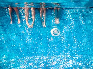 Underwater view of kids' legs dangling over community pool resurface